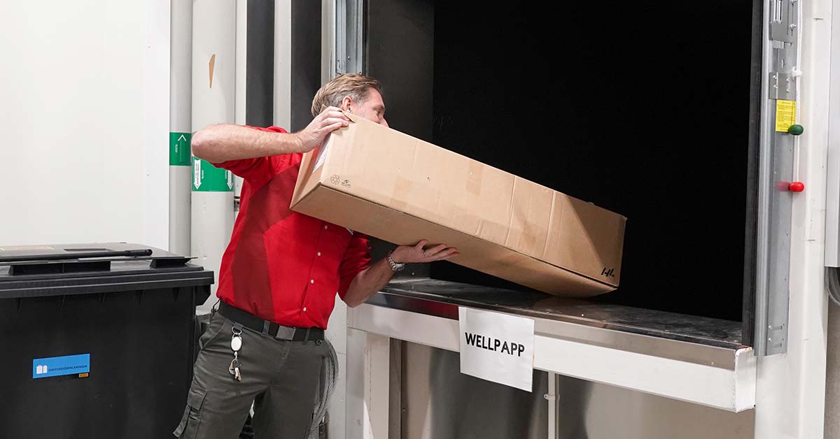 Man slänger kartong i komprimator