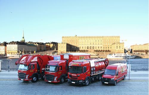fyra olika röda lastbilar står parkerade vid sidan av vägen i en stad